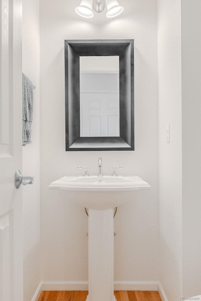 8367 Devinney St, Arvada, CO 80005 - bathroom featuring wood finished floors, baseboards, and a sink