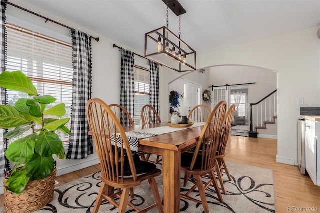 dining space with stairway, baseboards, a chandelier, and light wood finished floors