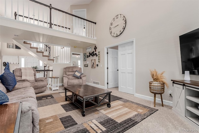 living room with visible vents, baseboards, a towering ceiling, and stairway