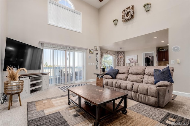 carpeted living area featuring baseboards and a towering ceiling