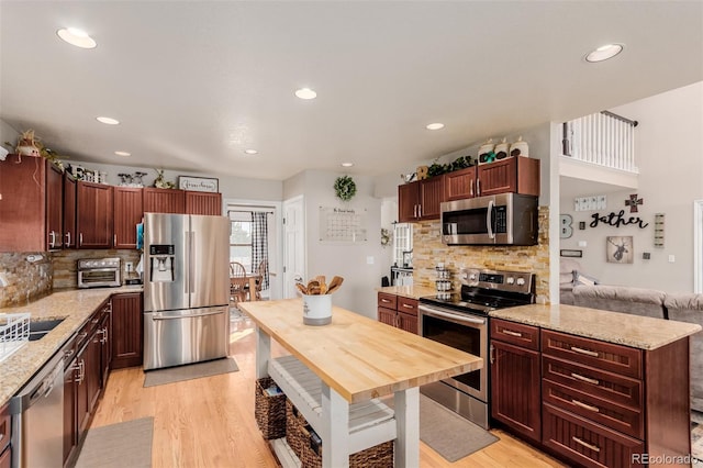 kitchen featuring light stone counters, light wood-style flooring, appliances with stainless steel finishes, and a sink