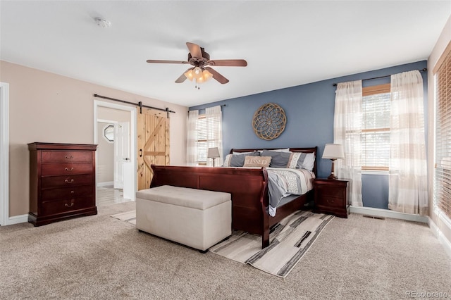 carpeted bedroom featuring visible vents, baseboards, a barn door, and a ceiling fan