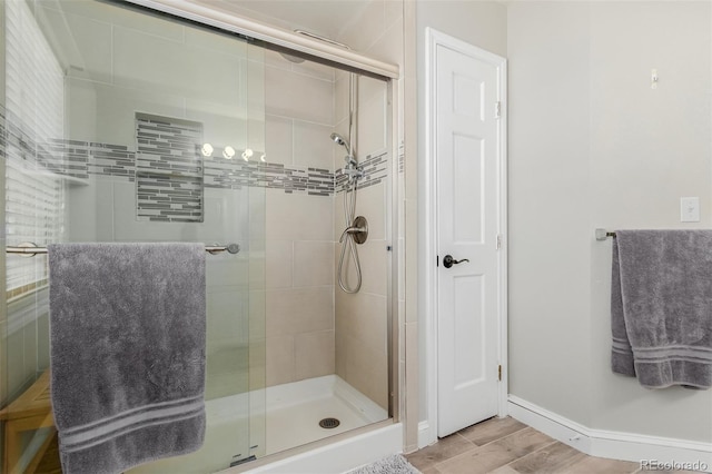 full bath featuring baseboards, wood finished floors, and a stall shower