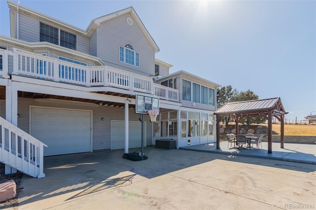 back of property with a gazebo, driveway, a garage, and a sunroom