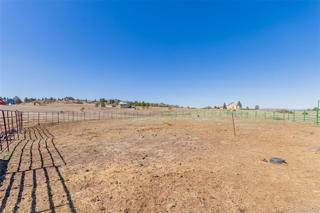 view of yard with an enclosed area, a rural view, and fence