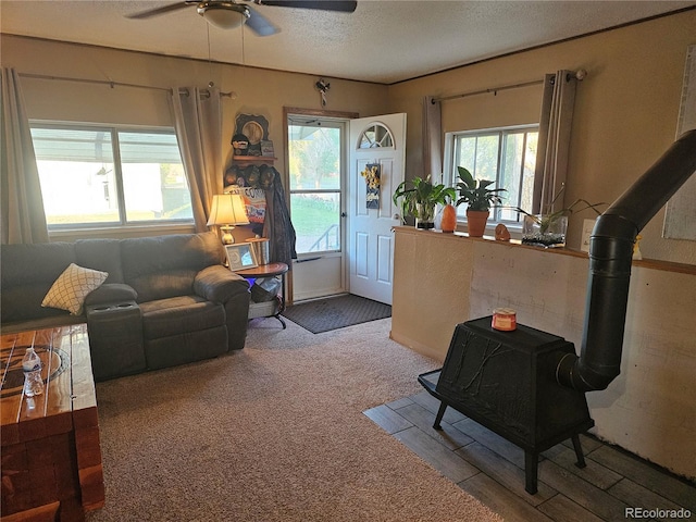 24797 Pleasant Hill Ave, Galeton, CO 80622 - carpeted living room featuring a wood stove, a ceiling fan, and a textured ceiling