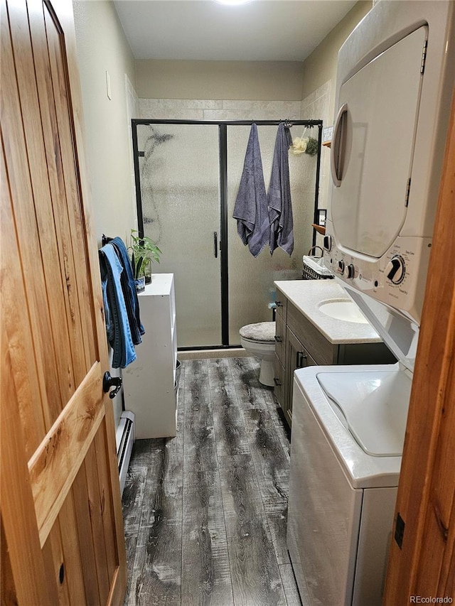 24797 Pleasant Hill Ave, Galeton, CO 80622 - bathroom with stacked washer and clothes dryer, hardwood / wood-style floors, a stall shower, a baseboard radiator, and toilet