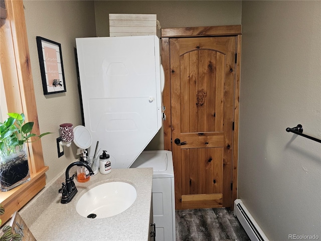 24797 Pleasant Hill Ave, Galeton, CO 80622 - bathroom with stacked washing machine and dryer, wood finished floors, vanity, and a baseboard radiator
