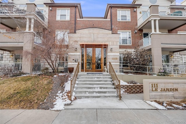 view of exterior entry featuring stone siding, french doors, and brick siding