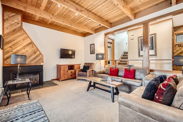 living room featuring beam ceiling, carpet flooring, wooden ceiling, wood walls, and a tiled fireplace