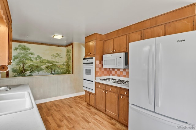 kitchen with decorative backsplash, light hardwood / wood-style floors, white appliances, and sink