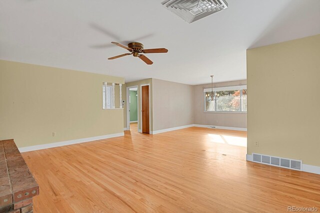 unfurnished living room featuring light hardwood / wood-style floors and ceiling fan with notable chandelier