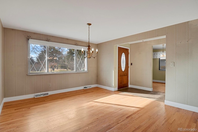 unfurnished dining area with hardwood / wood-style floors and an inviting chandelier