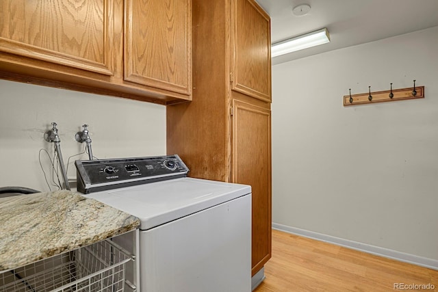 laundry room featuring light hardwood / wood-style floors, cabinets, and washer / dryer