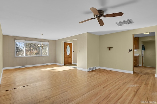 unfurnished living room featuring ceiling fan with notable chandelier and light wood-type flooring