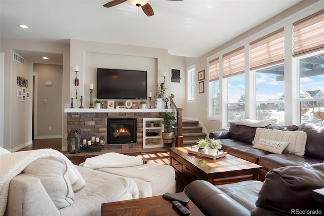 living area featuring ceiling fan, a stone fireplace, recessed lighting, visible vents, and stairway