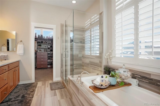 full bathroom with vanity, recessed lighting, a spacious closet, a garden tub, and a stall shower
