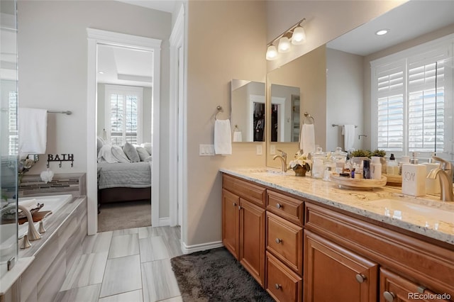 ensuite bathroom with a sink, a bath, ensuite bath, and double vanity