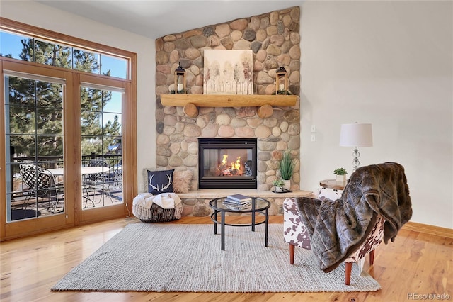 living room featuring lofted ceiling, a stone fireplace, and wood finished floors