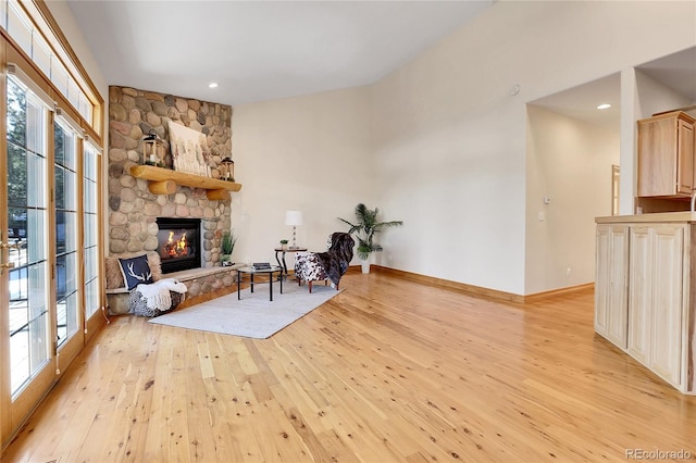 living area with light wood-style floors, recessed lighting, baseboards, and a stone fireplace