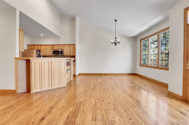 interior space featuring hanging light fixtures, stainless steel appliances, light countertops, light brown cabinetry, and light wood-style floors