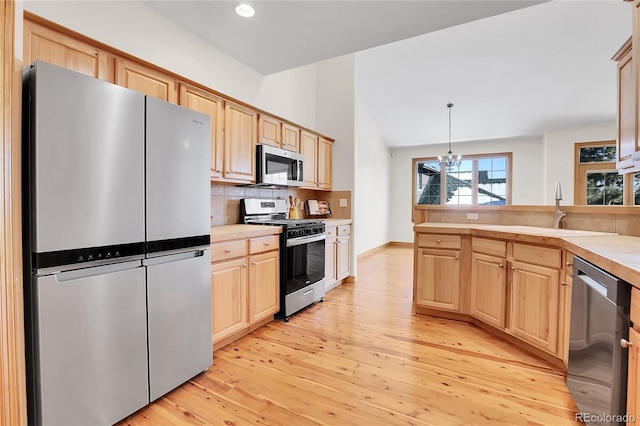 kitchen with decorative light fixtures, stainless steel appliances, lofted ceiling, decorative backsplash, and light brown cabinets