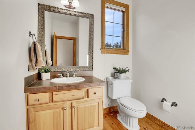 bathroom with baseboards, vanity, toilet, and wood finished floors