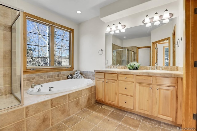 bathroom featuring a bath, a stall shower, double vanity, and a sink