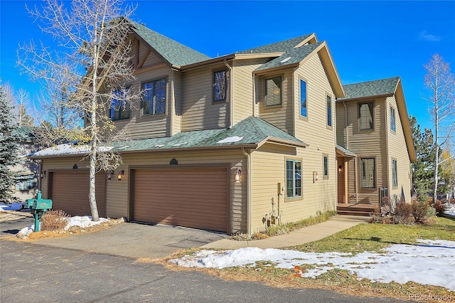 view of front of house with an attached garage, aphalt driveway, and roof with shingles