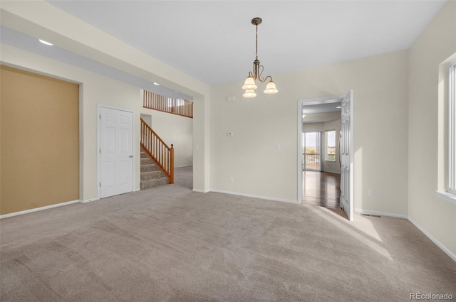 unfurnished room featuring light colored carpet and a chandelier