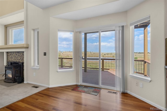 doorway featuring hardwood / wood-style flooring, a water view, and a wood stove