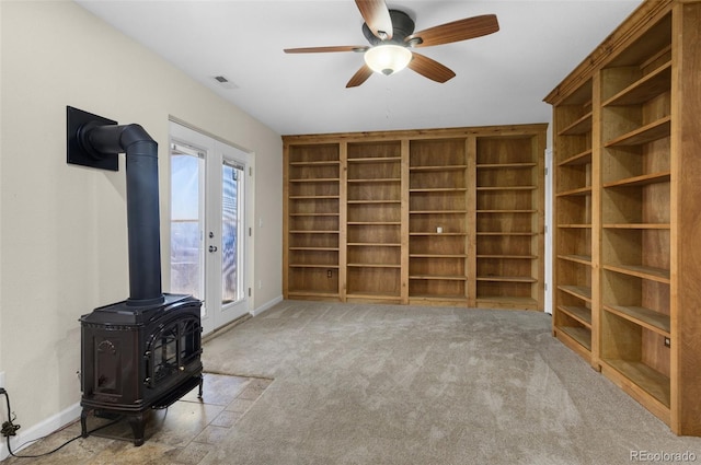 interior space featuring a wood stove, ceiling fan, and french doors