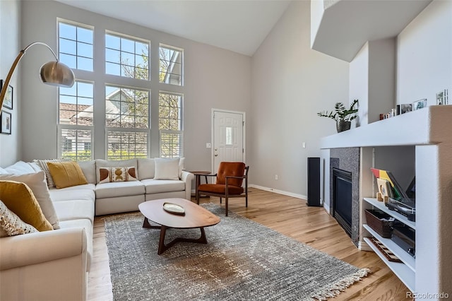 8300 Fairmount Dr Unit Aa102, Denver, CO 80247 - living room featuring high vaulted ceiling, a fireplace, light wood-type flooring, and baseboards