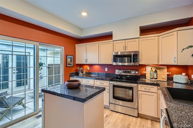 8300 Fairmount Dr Unit Aa102, Denver, CO 80247 - kitchen with appliances with stainless steel finishes, light wood-style flooring, a kitchen island, a sink, and tile countertops