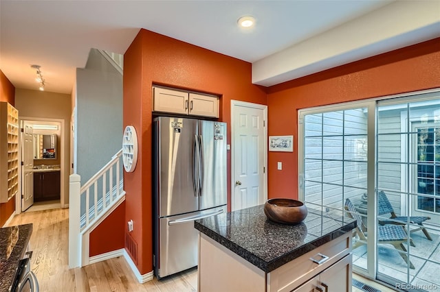 8300 Fairmount Dr Unit Aa102, Denver, CO 80247 - kitchen with freestanding refrigerator, light wood-style flooring, dark countertops, a center island, and baseboards