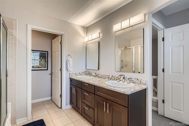 8300 Fairmount Dr Unit Aa102, Denver, CO 80247 - bathroom with a stall shower, tile patterned floors, double vanity, and a textured wall