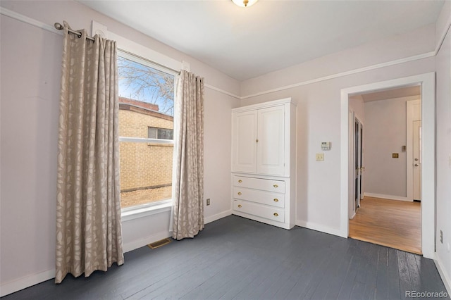 unfurnished bedroom with dark wood-type flooring and multiple windows