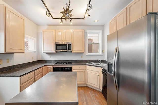 kitchen with sink, a wealth of natural light, black appliances, and light wood-type flooring