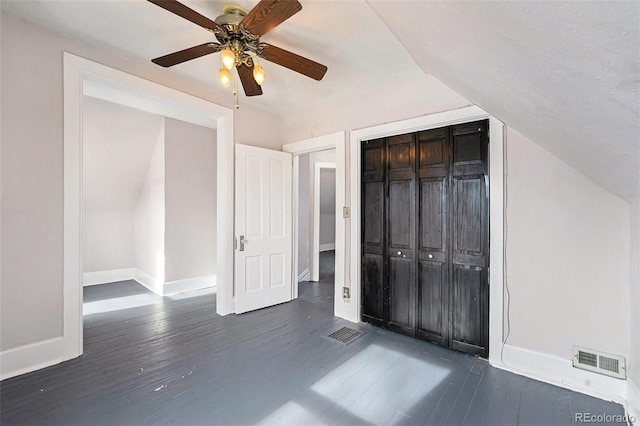 unfurnished bedroom with vaulted ceiling, ceiling fan, dark hardwood / wood-style flooring, and a closet