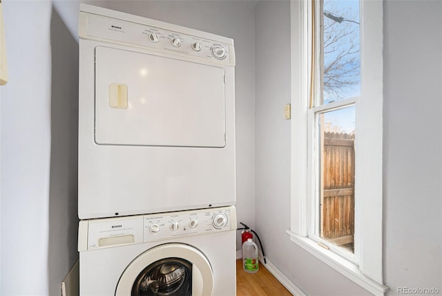 laundry area with stacked washer and clothes dryer and hardwood / wood-style floors