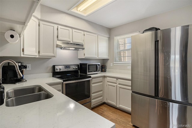 8259 S Fillmore Cir, Centennial, CO 80122 - kitchen featuring appliances with stainless steel finishes, under cabinet range hood, white cabinets, light countertops, and light wood finished floors