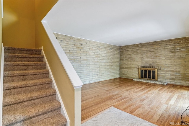 stairway with wood finished floors and a fireplace