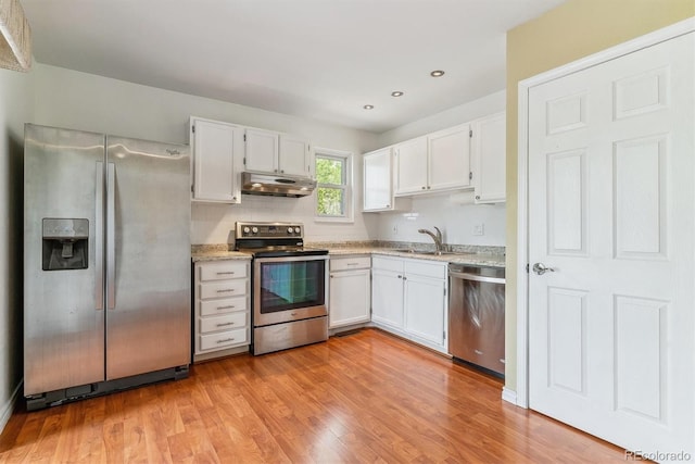 kitchen with stainless steel appliances, under cabinet range hood, a sink, white cabinetry, and recessed lighting
