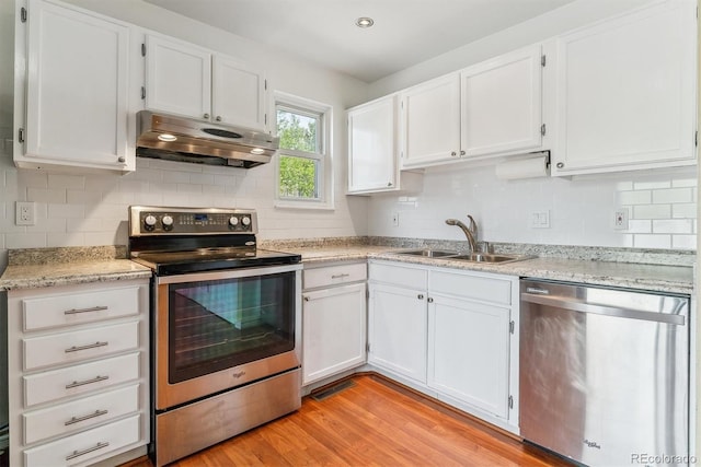 kitchen featuring appliances with stainless steel finishes, under cabinet range hood, a sink, and white cabinets
