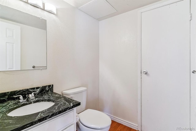half bath with vanity, toilet, and wood finished floors