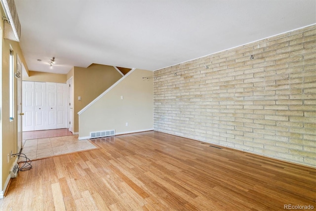 1160 S Clinton St Unit 40, Denver, CO 80247 - unfurnished living room featuring brick wall, wood finished floors, baseboards, and stairway