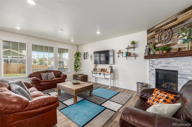 living room featuring a textured ceiling, light wood-type flooring, and a fireplace