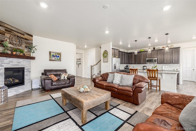 living room with light hardwood / wood-style floors and a stone fireplace