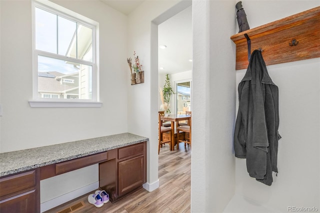 mudroom featuring built in desk and light hardwood / wood-style flooring