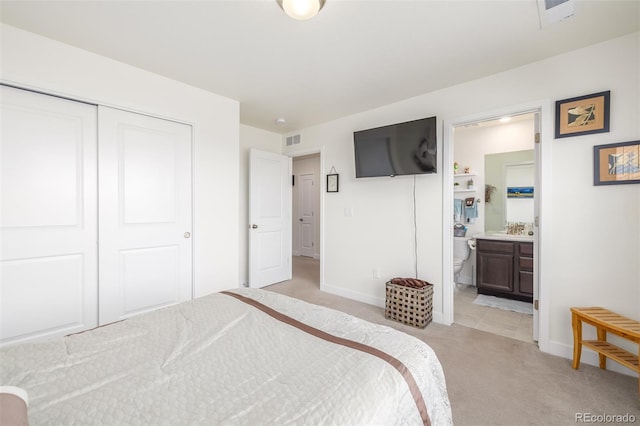 bedroom featuring light carpet, a closet, sink, and connected bathroom